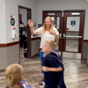 Teacher greeting students as they walk through a school hallway