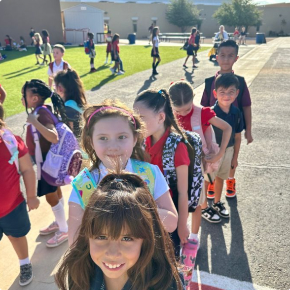 Elementary students walking in a line outdoors on a sunny school day